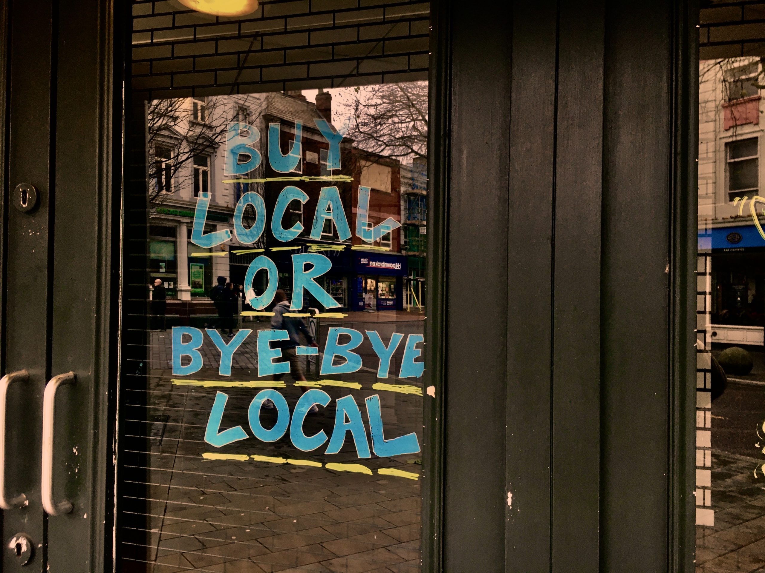 Buy Local or Bye-Bye Local written on shop doors